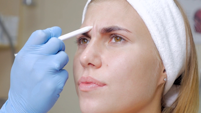 A Professional Marking the Area for A Beauty Procedure on A Woman's Eyebrow