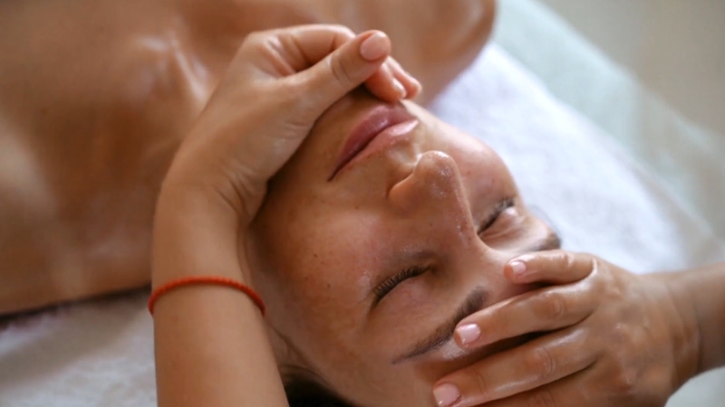 A woman receives a facial massage, relaxing and promoting skin rejuvenation