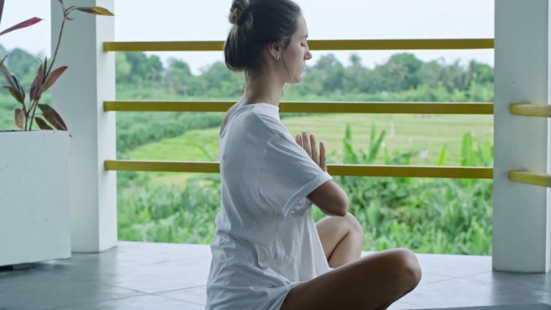 A woman practices meditation outdoors, enjoying the calming effects of stress management on her skin