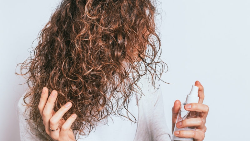 A person applying a styling product to their curly hair