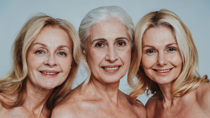 Three confident, smiling women in midlife showing natural beauty and wellness during menopause