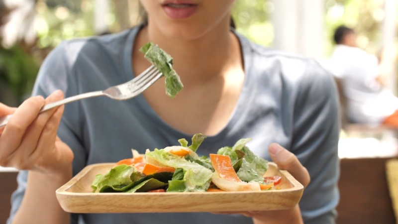A person eating a salad while highlighting the importance of diet during menopause
