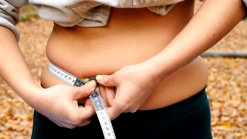 A person measuring their waist to track gaining weight during menopause