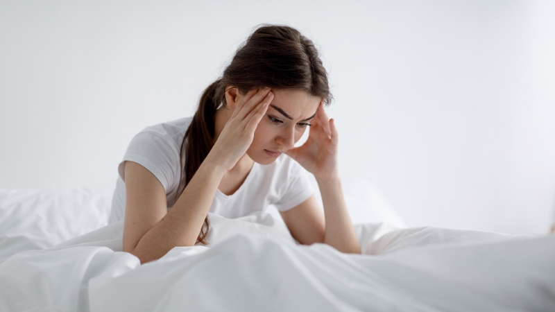 Tired woman in bed showing effects of low estrogen on skin health