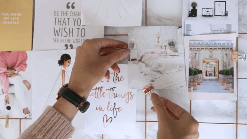 Hands pin inspirational images and quotes to a vision board, focusing on life goals and adventures after 50