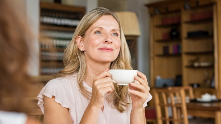 A woman drinking coffee and thinking about confidence boosters for women over 40