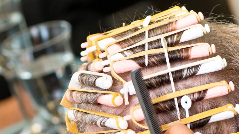 Hair wrapped around perm rods to create curls on bleached hair with care and precision