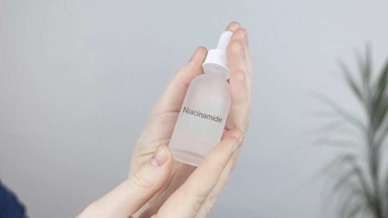 A person holds a clear bottle of niacinamide serum, illustrating the question “does niacinamide expire” about skincare shelf life
