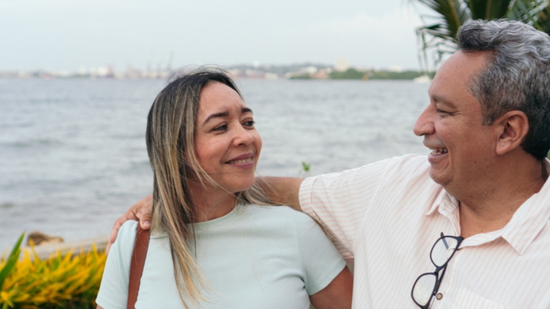 Middle-aged couple smiling and talking by the water, showing honest and open communication