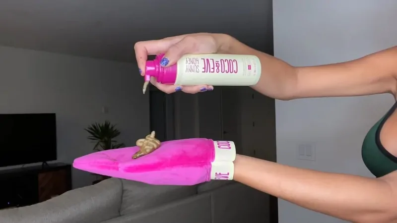 Person applying self tanner mousse onto a pink mitt before use