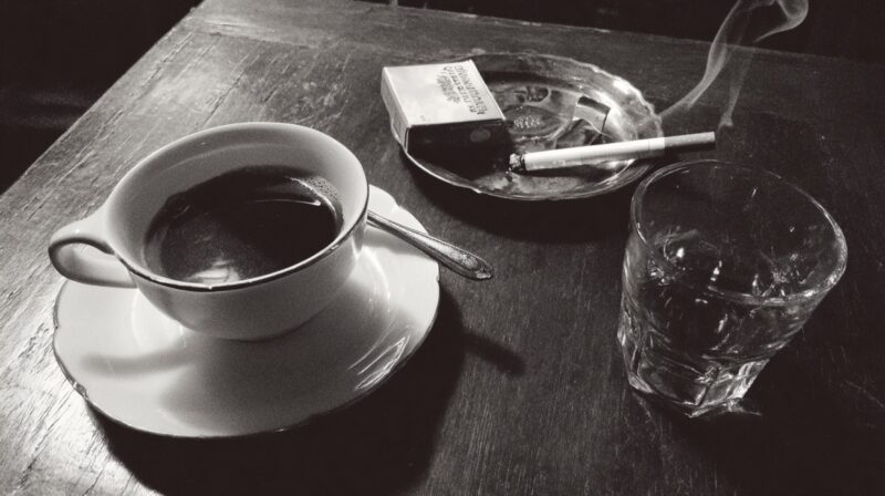 Cup of coffee, cigarette and glass of alcohol on table