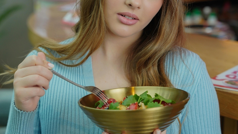 A woman eats a salad, reflecting everyday choices tied to a viral health trend diet