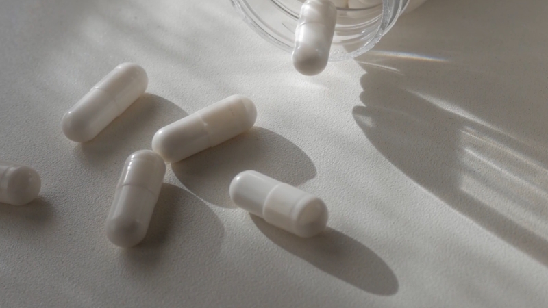 White magnesium capsules scattered near an open supplement bottle on a table