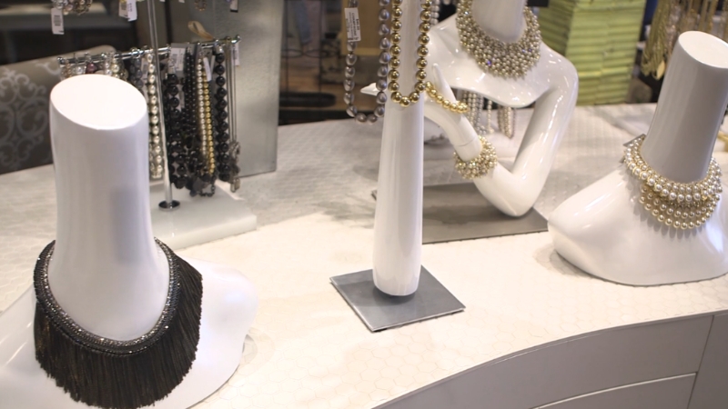 Necklaces and bracelets displayed on white stands inside a jewelry store