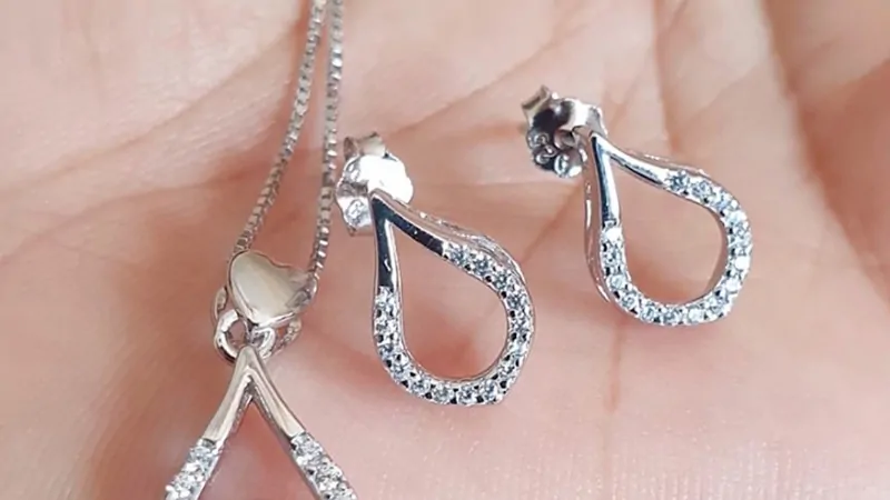 Sterling silver earrings and a matching pendant held in an open hand for a close-up view