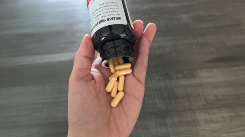 A hand pours vitamin B12 capsules from a supplement bottle