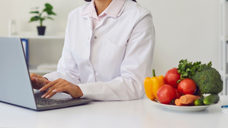 A health professional reviews nutrition information beside fresh foods, highlighting the role of real credentials