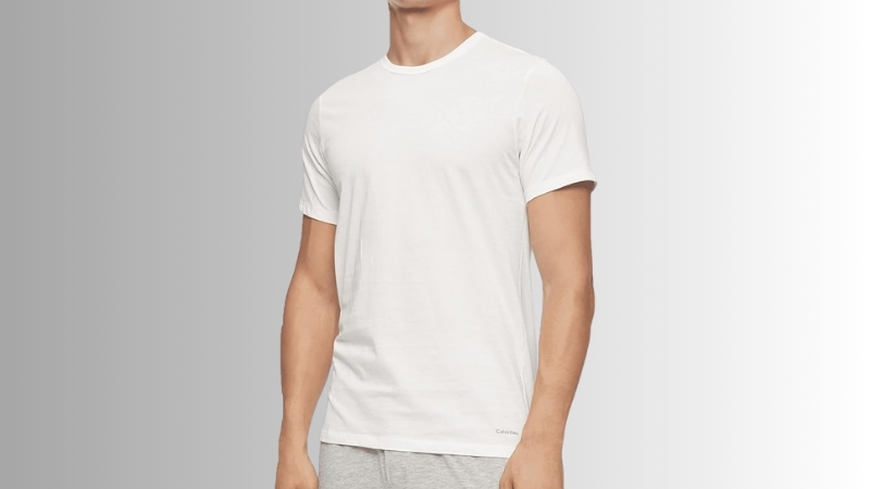 Man wearing a white Calvin Klein cotton undershirt against a neutral background
